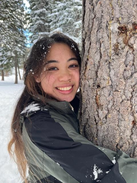 Photo of Allison hugging a tree in the snow. 